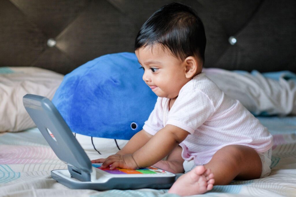 Serious-faced baby working on toy laptop computer